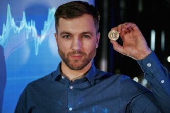 A person holds a digital currency coin in their hand while standing in front of a projector displaying data.