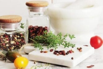 Close-up of various dried herbs and spices scattered on a wooden kitchen table.