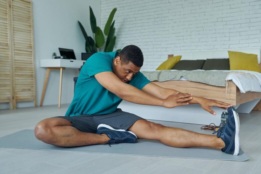 A young multiracial man in athletic wear exercises confidently in a home setting.