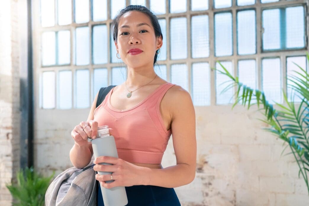 Young woman in athletic wear holding a water bottle, ready for exercise.