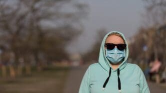 Woman wearing a protective mask stands at a safe distance, illustrating the concept of social distancing.