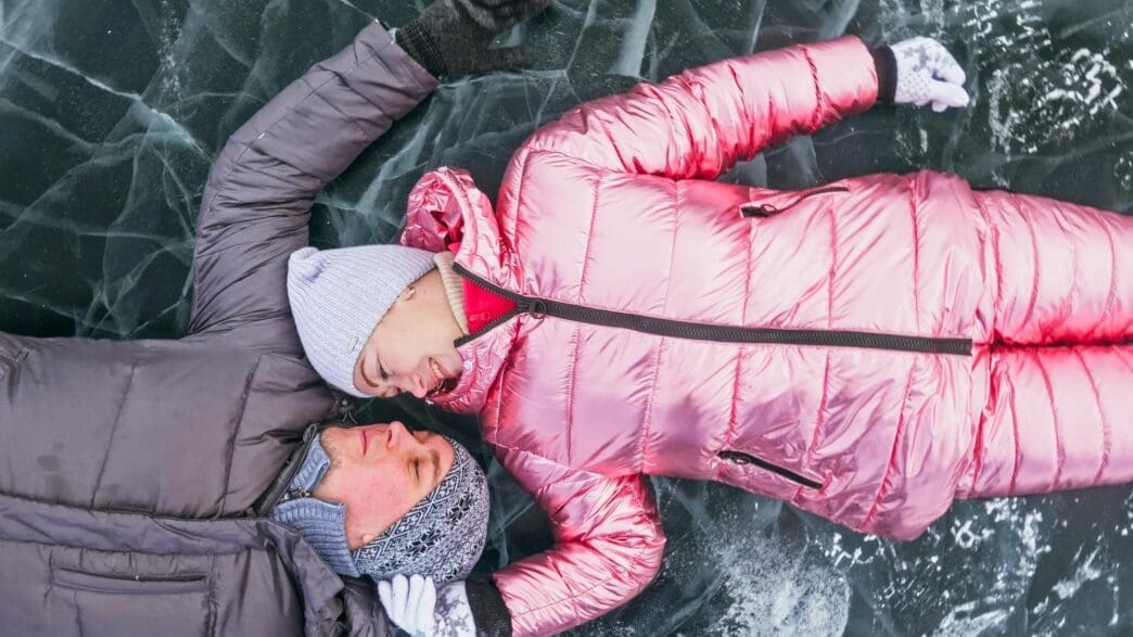 A couple laughs and enjoys a winter walk, silhouetted against a backdrop of ice.
