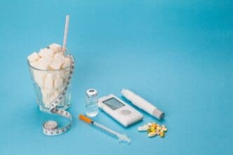 A medical concept image shows insulin syringes and pills next to a measuring tape and a glass filled with sugar cubes.