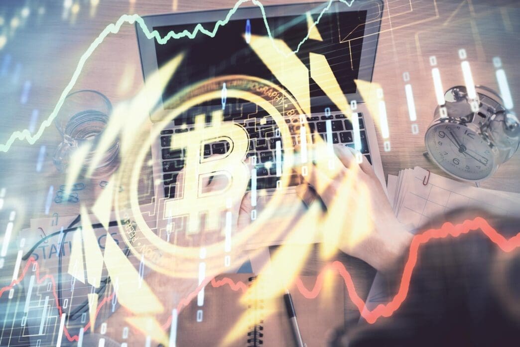 Double exposure of a person's hands typing on a keyboard with a cryptocurrency-themed hologram overlaid.