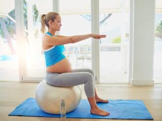Pregnant woman using an exercise ball for a prenatal pilates workout.