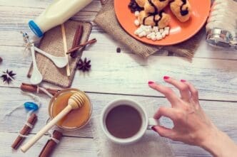 A woman's hand cradles a steaming mug of coffee.