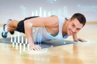 A smiling man does push-ups on the floor in a gym.