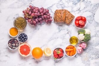 Overhead view of a colorful assortment of fresh fruits and vegetables, including berries, leafy greens, and cruciferous vegetables.