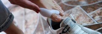 Close-up of a woman's feet with hallux valgus, highlighting the deformity as she puts on sneakers.