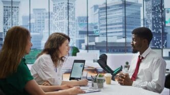 A team of HR recruiters interviews a candidate using crutches in a modern office setting.