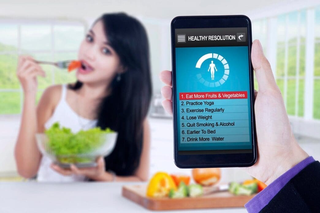 Woman eats a salad while looking at a list of healthy resolutions.