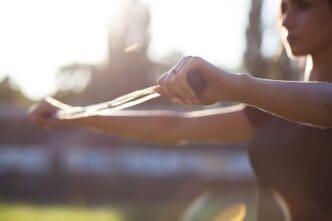 A woman in fitness attire stretches with a jump rope on a stadium track.