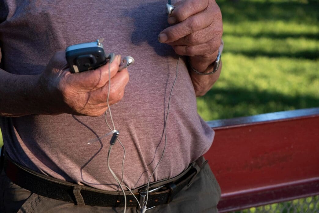 A senior adult man holds a radio in the lower portion of the image.