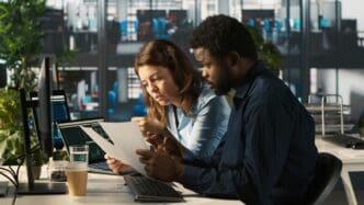 A manager at an office desk reviews documents with an accountant.
