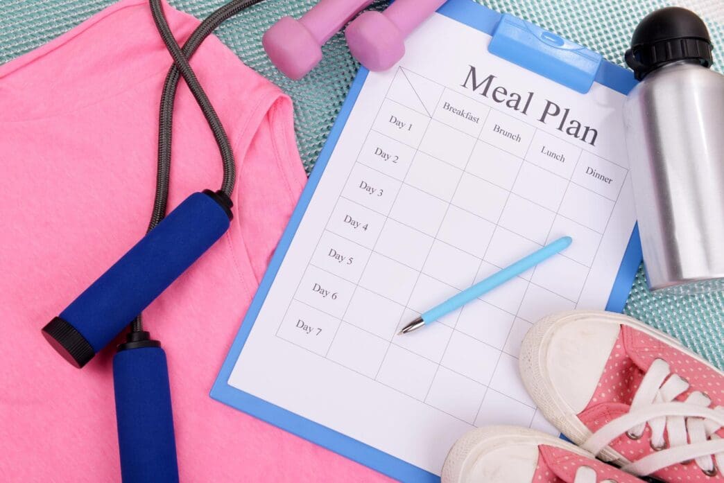 Top-down view of a meal plan next to sports equipment, likely for a healthy lifestyle.