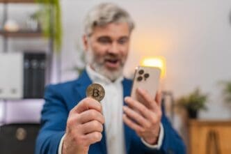 Middle-aged businessman, excited by a Bitcoin rally, gestures with enthusiasm while looking at a crypto app on his smartphone.