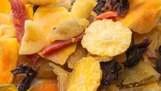 Close-up of a mix of dried exotic fruits including mango slices, pineapple, passion fruit, and papaya.