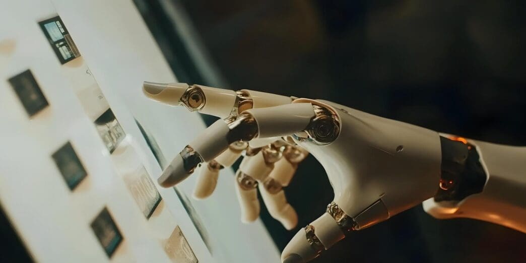 A robotic hand with a metallic finish is interacting with a touchscreen, likely performing a task or displaying information.