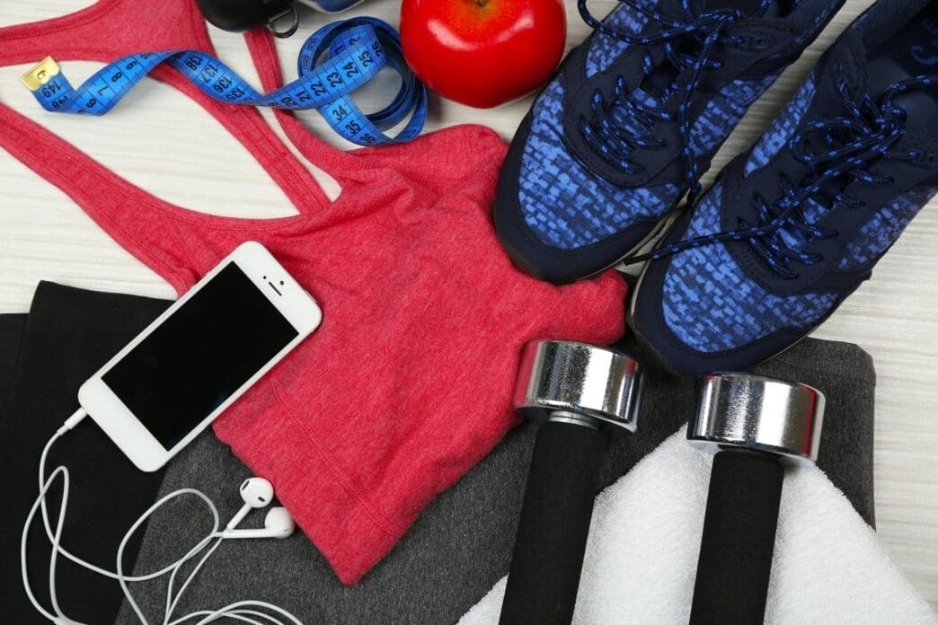 A collection of sports equipment, including a ball, shoes, and a water bottle, is arranged on a light-colored surface.