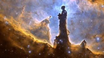 Silhouette of a person standing and looking at a colorful nebula filled with stars.