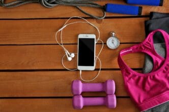 A collection of sports equipment and clothing, along with a mobile phone, are arranged on a wooden surface.