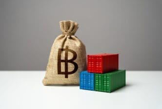 A money bag with the Thai baht symbol sits in front of shipping containers on a ship, representing import or export.