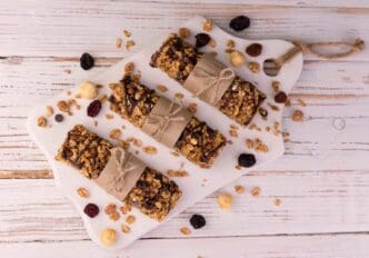 Three granola cereal bars arranged on a white wooden surface.