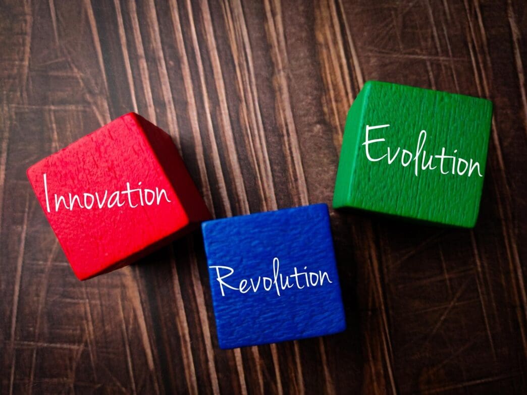 Top-down view of a wooden block with the words "Innovationrevolutionevolution rkers" carved into it, set against a wooden background.