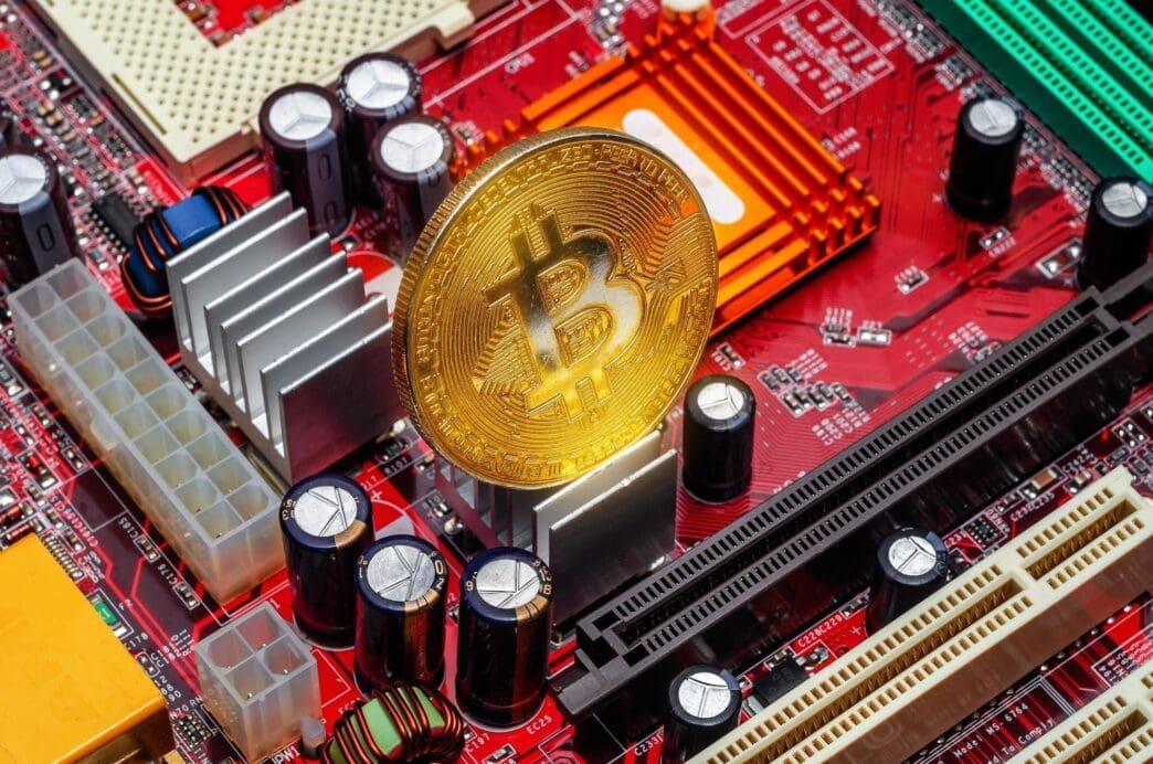 Top-down view of a golden bitcoin on a computer circuit board, likely representing a cryptocurrency mining farm.