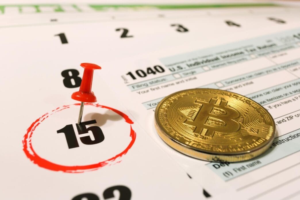 A graphic depicts a U.S. tax form with Bitcoin logos and the date April 15, 2019.