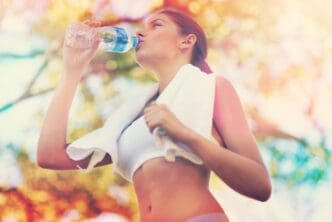 A young woman drinks water from a bottle after exercising.