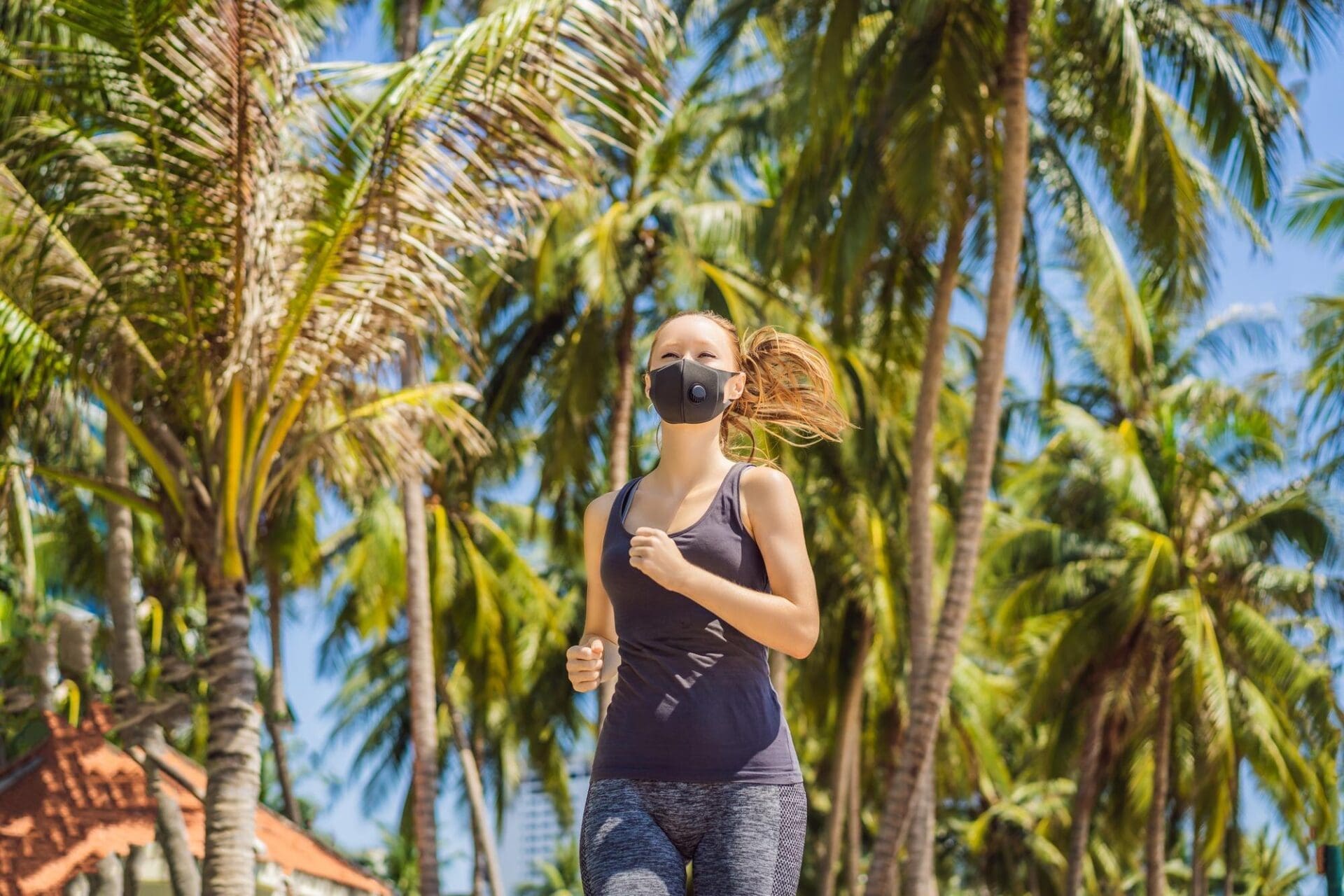 Woman wearing a medical mask runs through a city street, with buildings visible in the background.