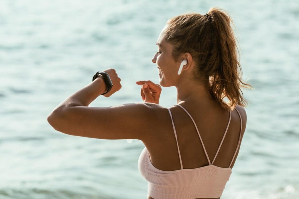 Woman wearing a smartwatch and exercising on a beach.