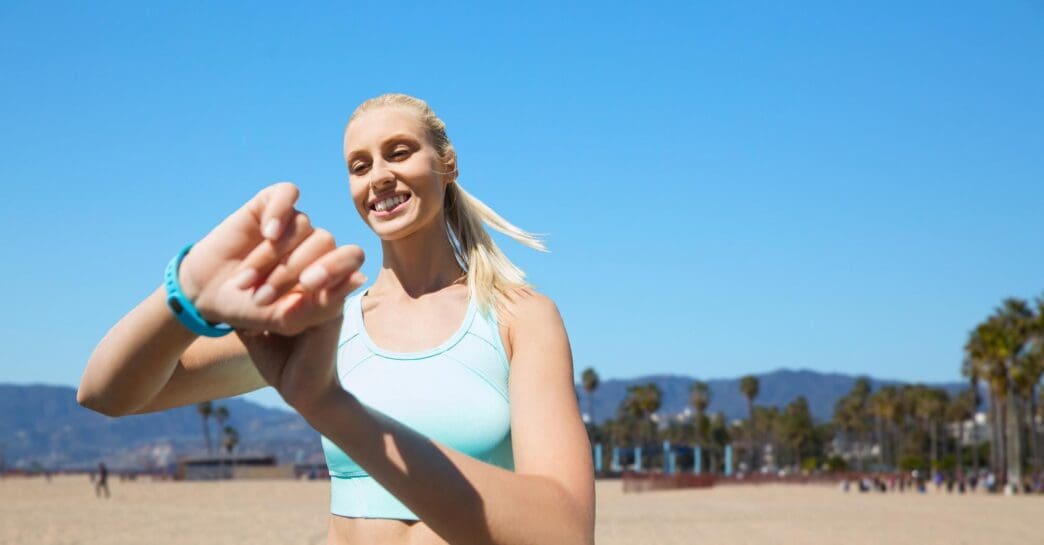 A woman wearing a fitness tracker exercises outside.