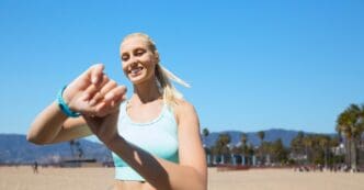 A woman wearing a fitness tracker exercises outside.