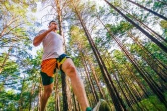 A young man in athletic wear jogs through a park.
