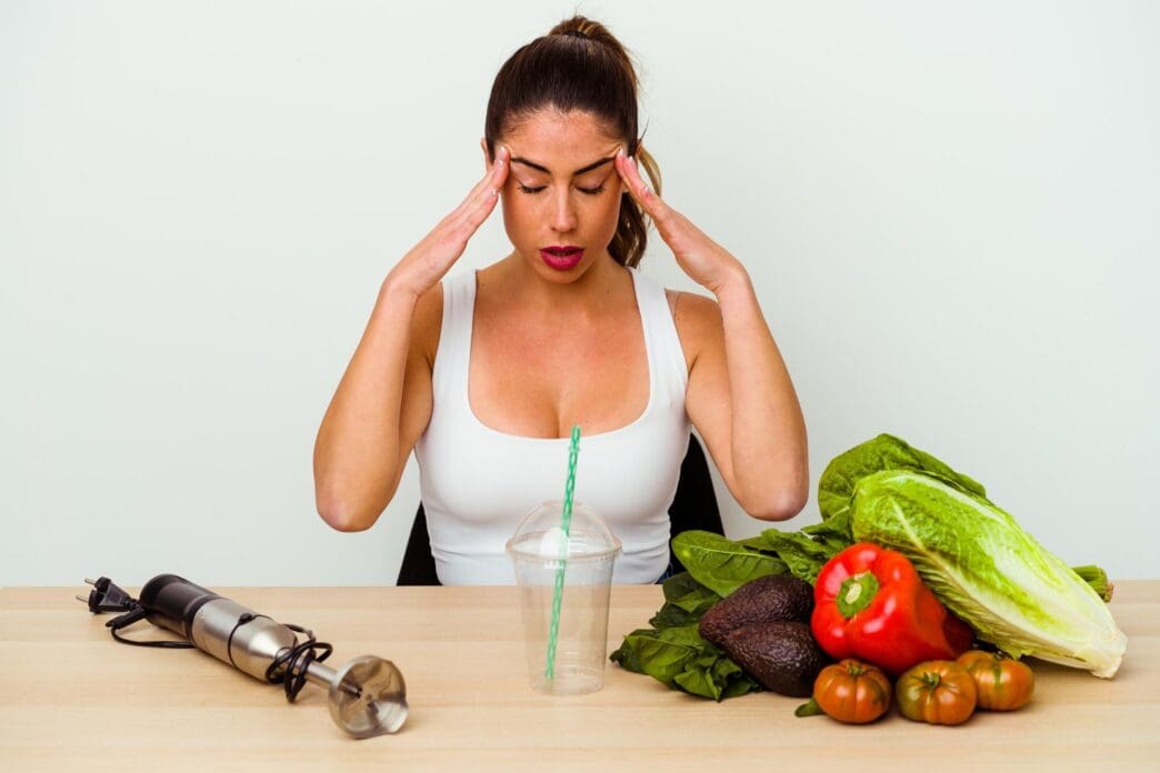 A young white woman prepares a green smoothie with vegetables.