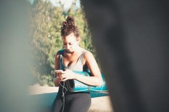 A young woman stands with her back to the camera, gazing towards the sky.