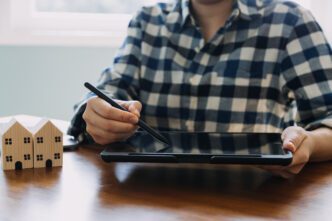 A real estate agent and client sign home sales and insurance contracts.