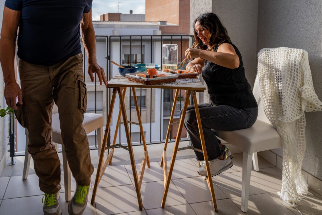 Middle-aged couple enjoys Chinese takeout at a table set on a city balcony.