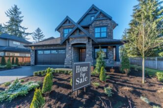 A "Home For Sale" sign is in front of a newly built house.