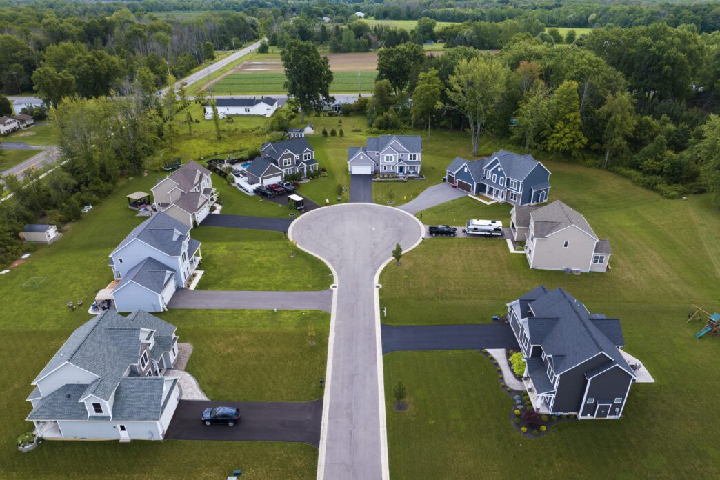 Aerial view of a suburban Rochester, NY neighborhood featuring a grid of large, newly built houses.