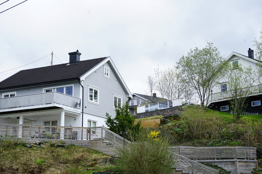 Modern houses with large windows are built into a green hillside.