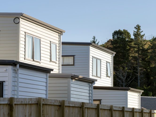 Row of modern, multi-story townhouses, likely public social housing, with identical facades and small front yards.