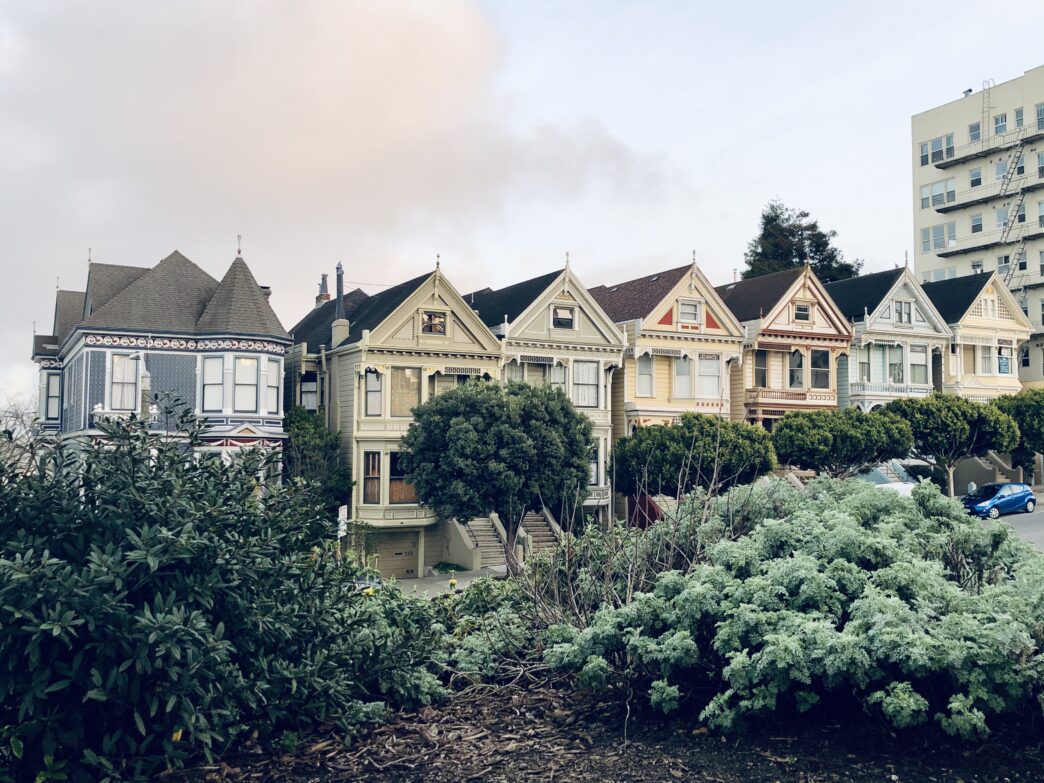 Trees and buildings are silhouetted against a bright sky.