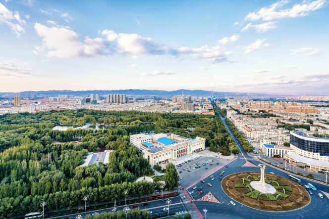 Aerial view of Baotou City showing a large roundabout, central park, and dense urban development.