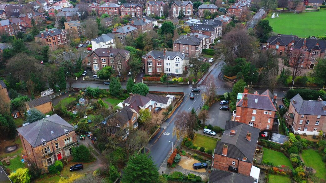 Aerial view of a dense, older suburban neighborhood in the UK with brick homes and winding roads.
