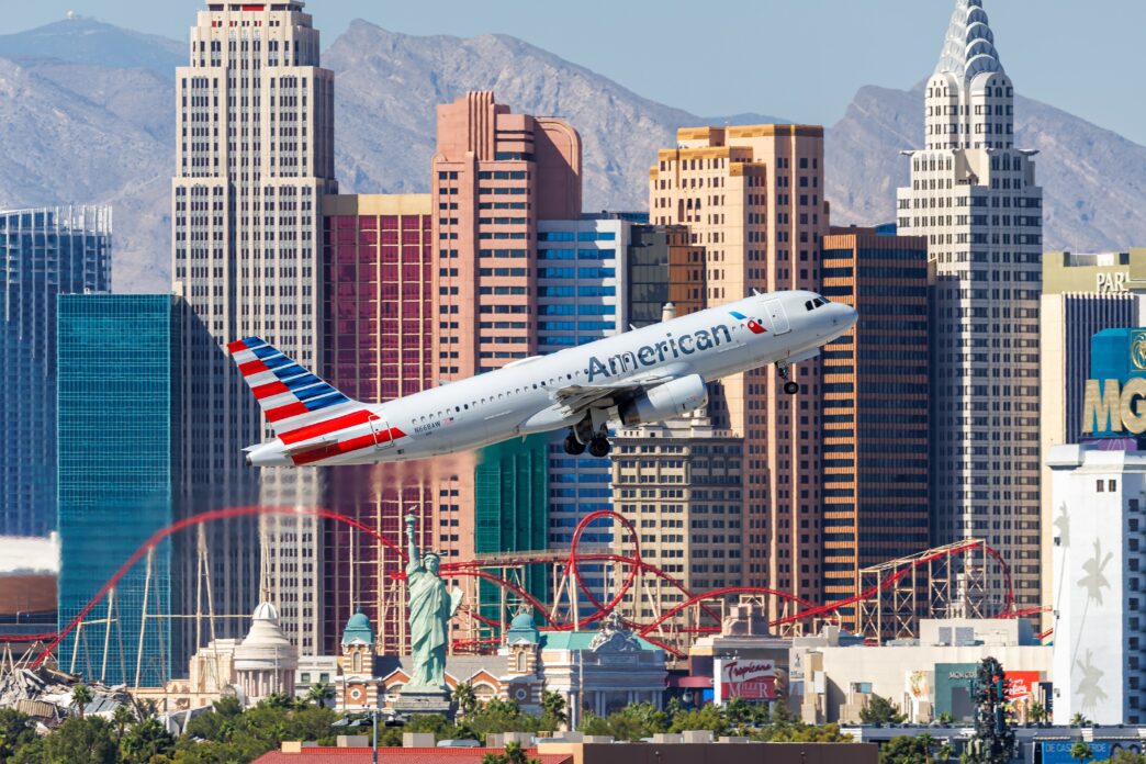 American Airlines Airbus A320 taking off over the Las Vegas strip skyline and Statue of Liberty replica.