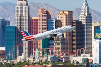 American Airlines Airbus A320 taking off over the Las Vegas strip skyline and Statue of Liberty replica.