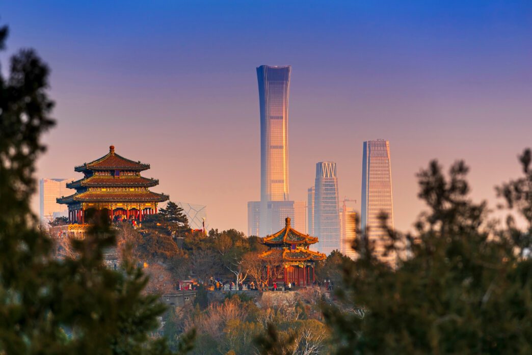 Beijing cityscape contrasting ancient pagodas with modern skyscrapers at sunset.